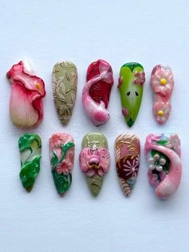 A flat-lay of ten handmade press-on nails in sage green and blush pink with sculpted three-dimensional flowers and leaves.
